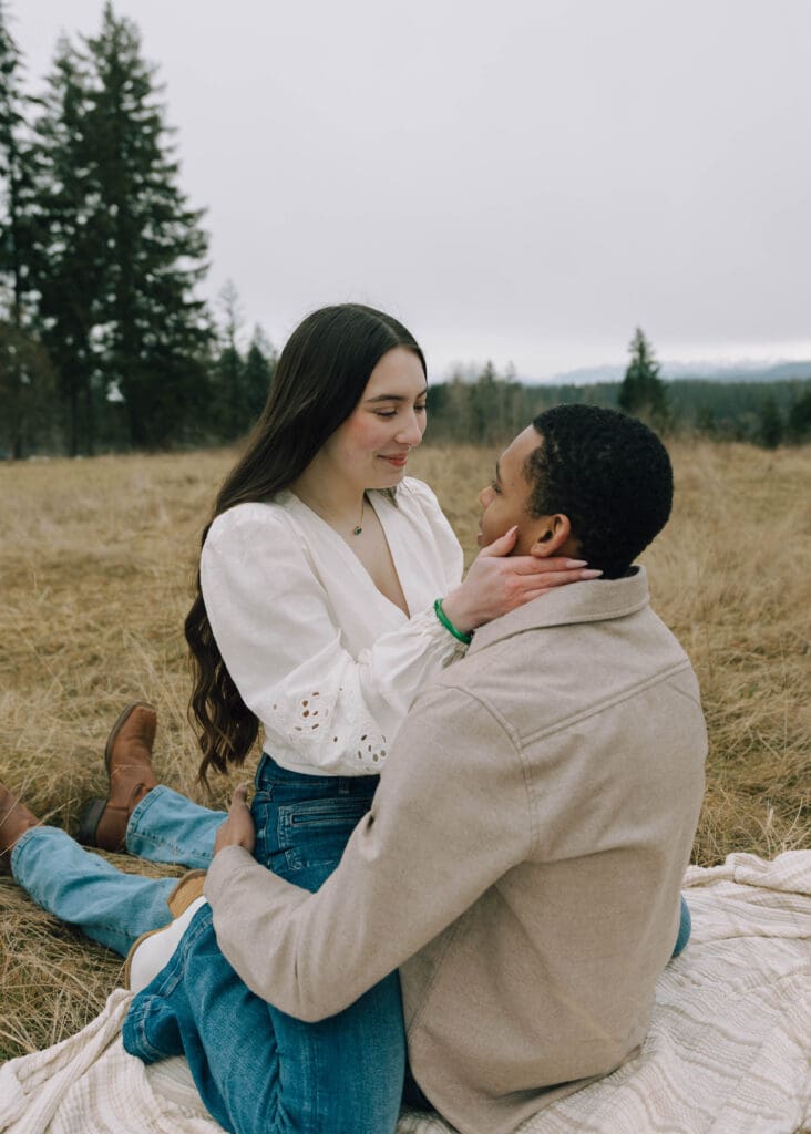 engaged couple straddling in a field in washington