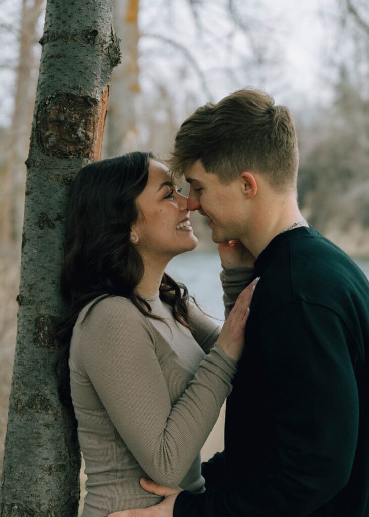 couple leaning against a tree almost kissing 