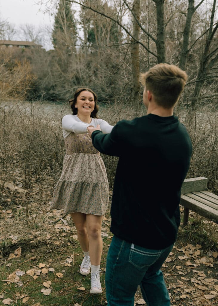 couple swing dance in the forest during engagement photo session 