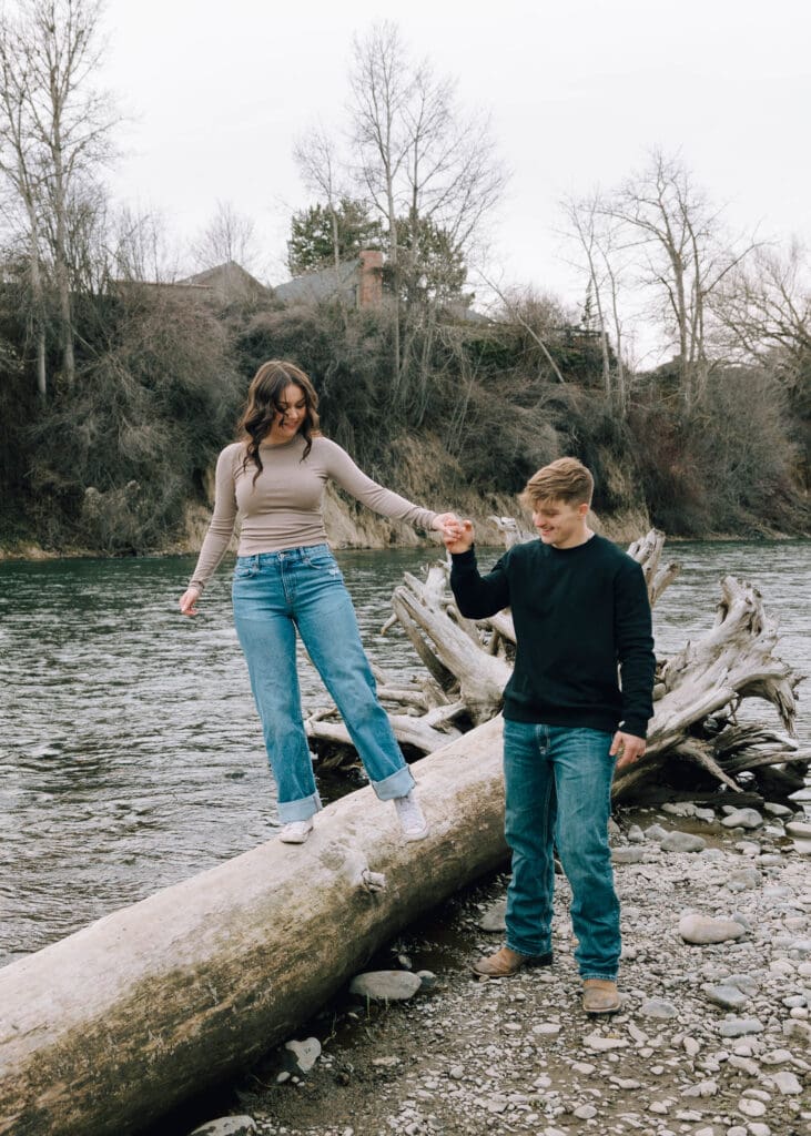 woman walking on the log holding boyfriends hand on the yakima river