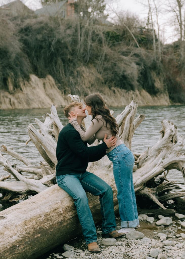couple leaning in to kiss at a log on the yakima river 