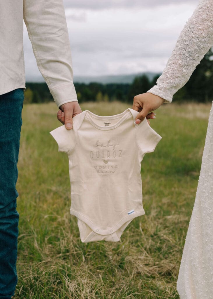 couple holding a cream onesie between them outside in Washington