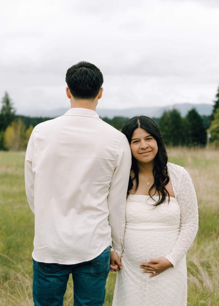woman holding her husbands arm and leaning on him holding her baby bump at Tanwax country chapel 