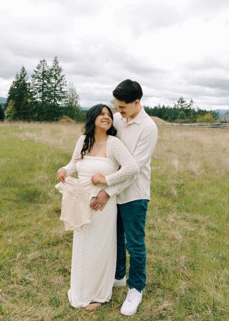 couple in white holding cream onesie with man holding his wife from behind in Washington