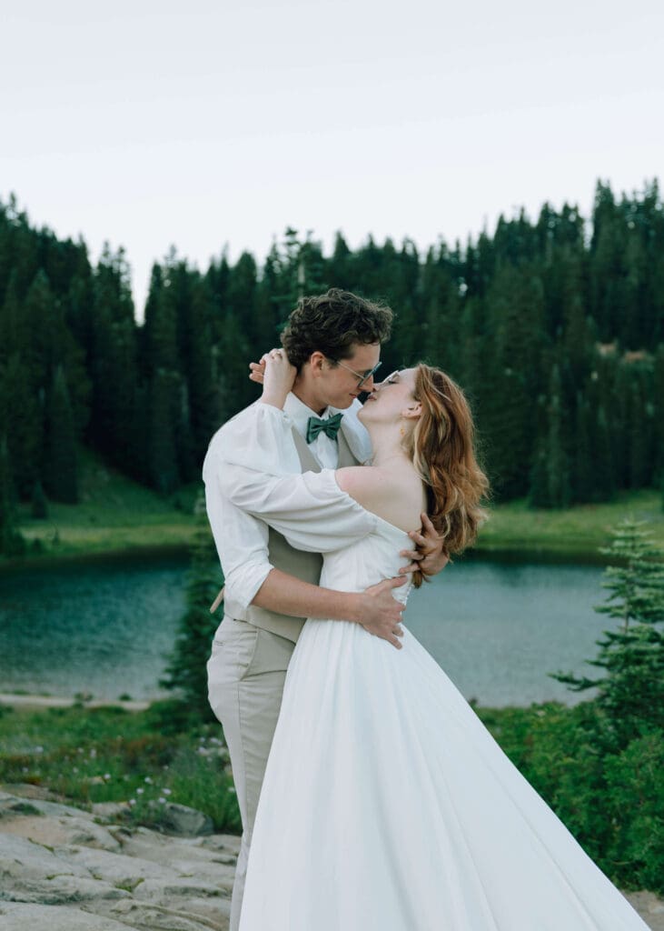 bride and groom holding each other on overlook in front of Lake Tipsoo