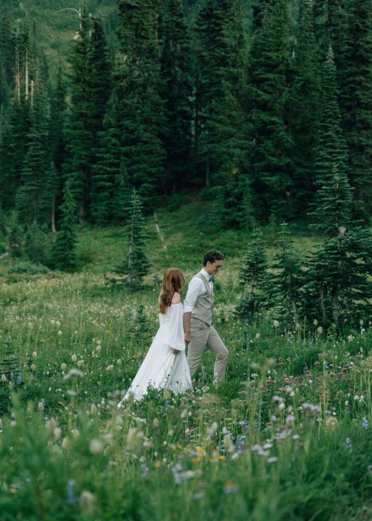 couple holding hands and walking through the meadow at mt rainier national park elopement 