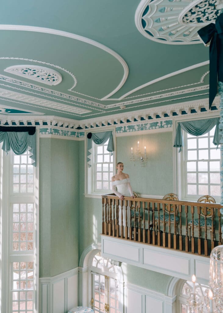 bride standing at the rail in the blue room with large windows for ceremony at estate at river run