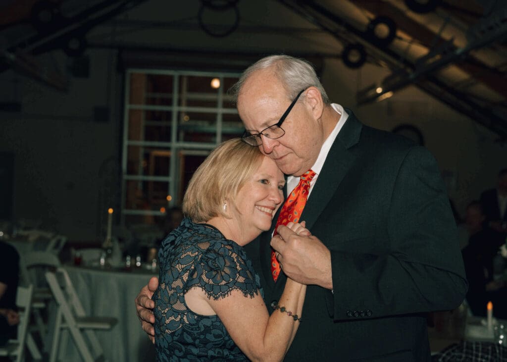 parents of the groom holding hands and dancing at wedding reception at Pickering barn