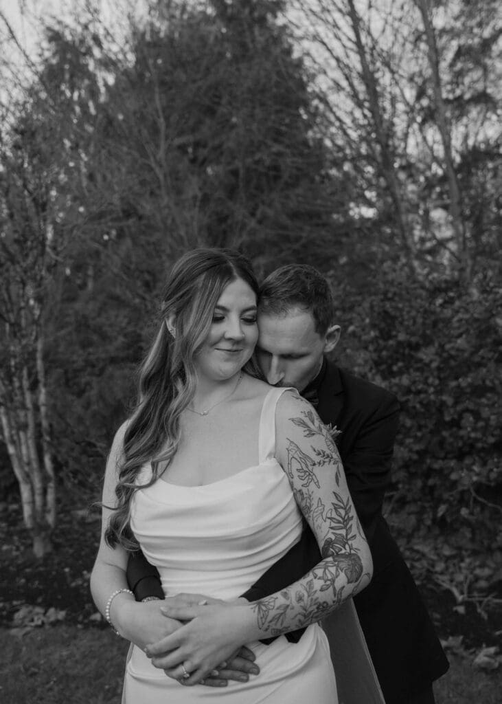 groom behind the bride kissing her on the shoulder outside at Pickering Barn 