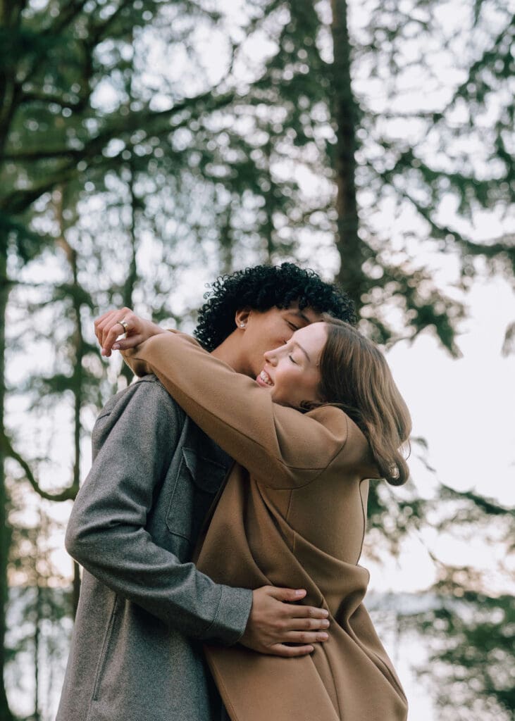 man kissing his girlfriend on the cheek at Owen beach engagement in winter 