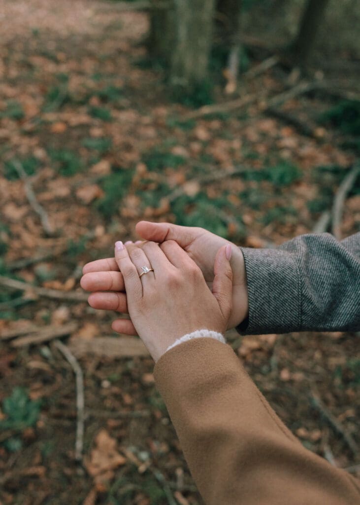 man holding his fiance's hand and showing off her engagement ring at Owen beach engagement 