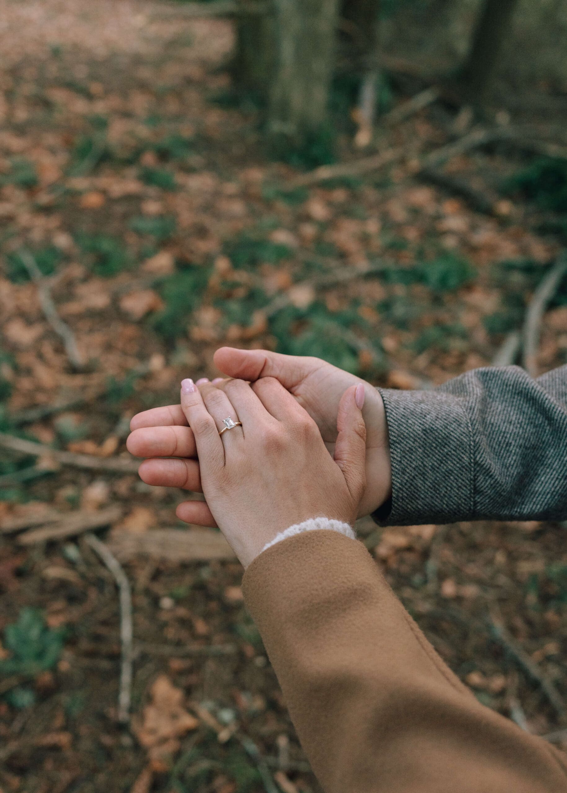 man holding his fiance's hand and showing off her engagement ring at Owen beach engagement