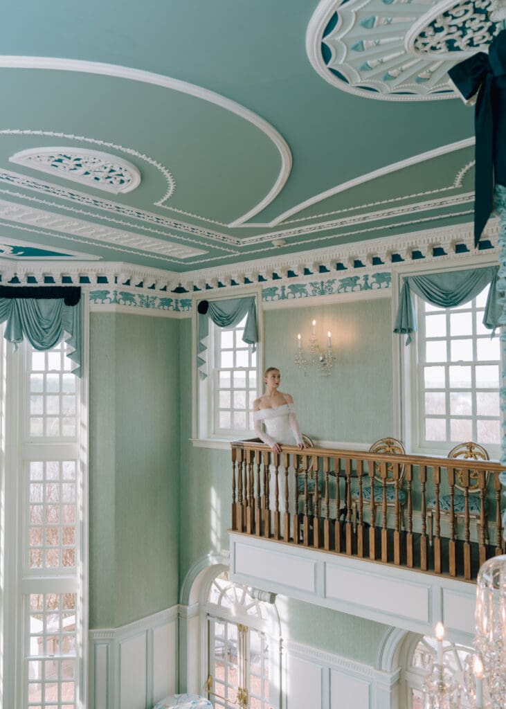 bride standing behind rail in blue room at wedding venue 