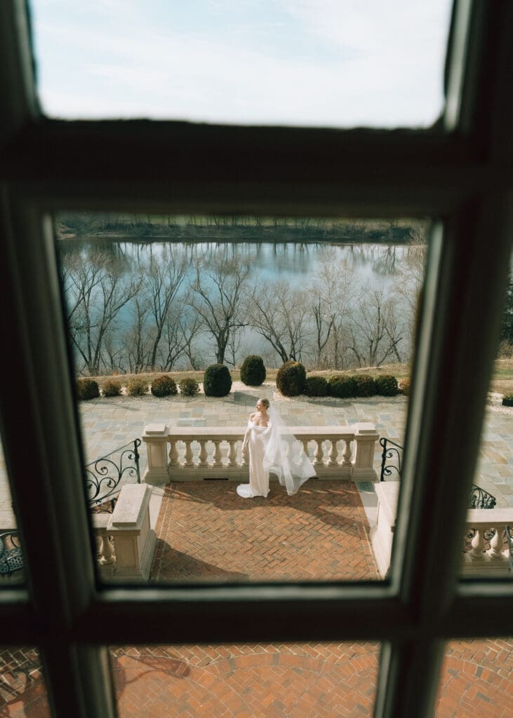 bride standing on terrace and photo being taken through a window 