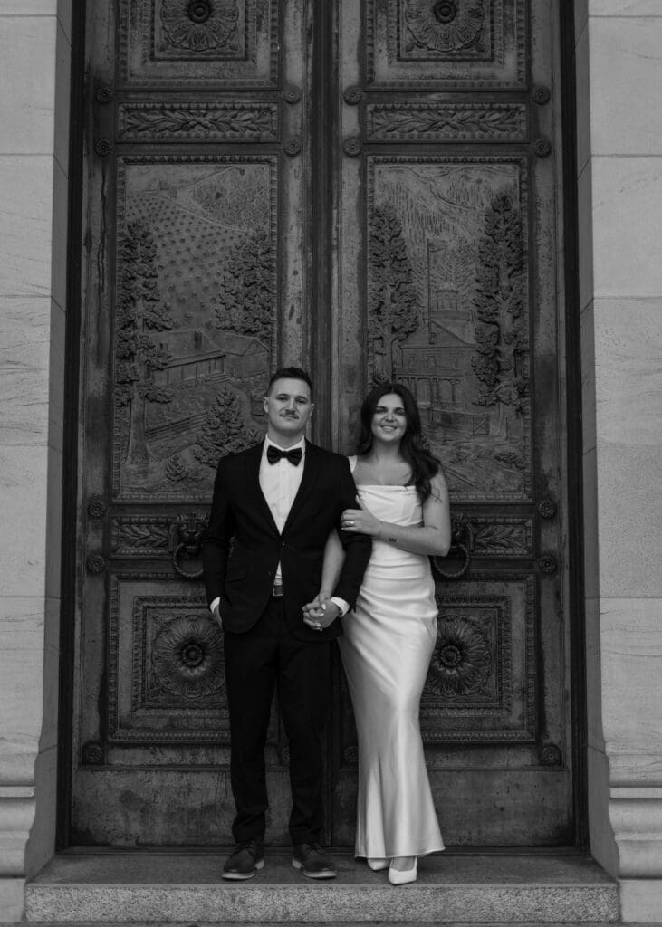 couple holding hands and standing in front of the double doors at the Washington state capitol engagement 