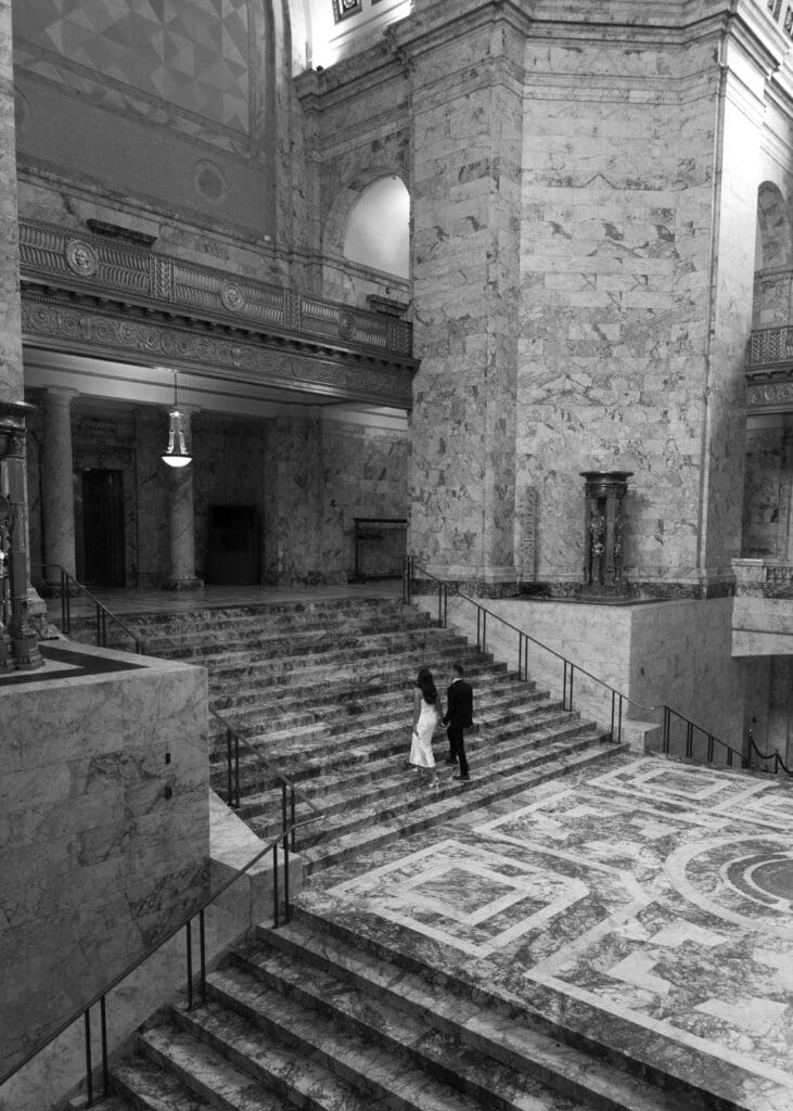 couple holding hands and walking up steps at washington state capitol wedding