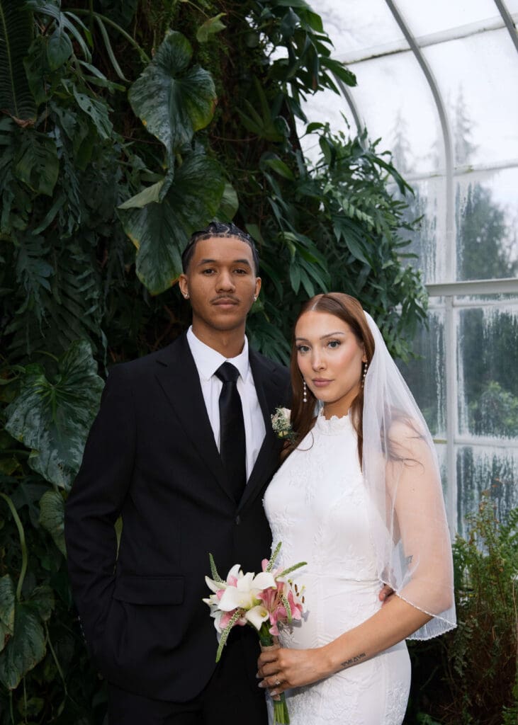 bride and groom posing for bridal portraits with bouquet in WW Seymour Botanical Conservatory