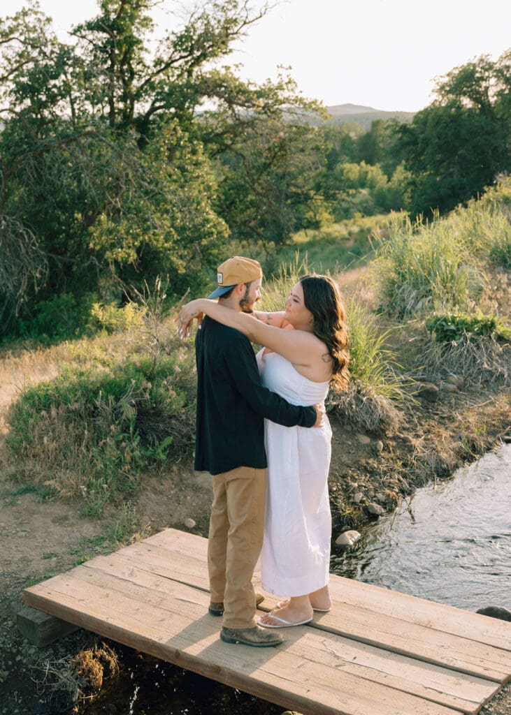 woman wraps arms around her man on a bridge in the summer in Yakima