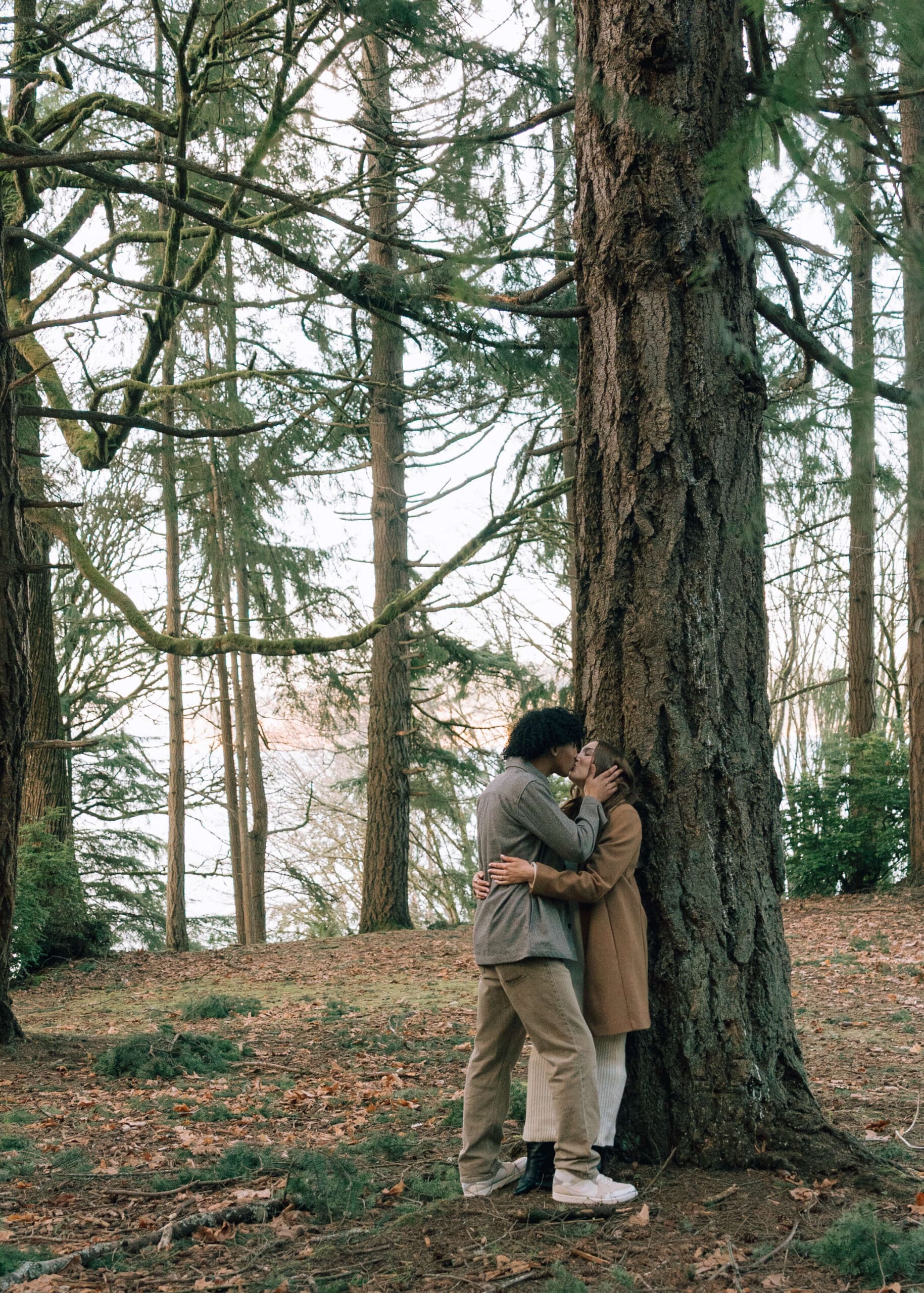 couple kissing against a tree at a park in Washington state