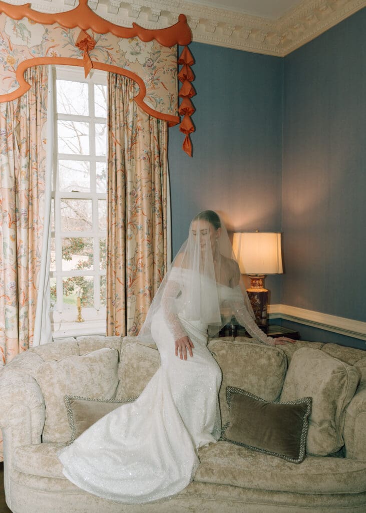 bride sitting on a couch with veil over her face at mansion venue design by Tacoma wedding planner