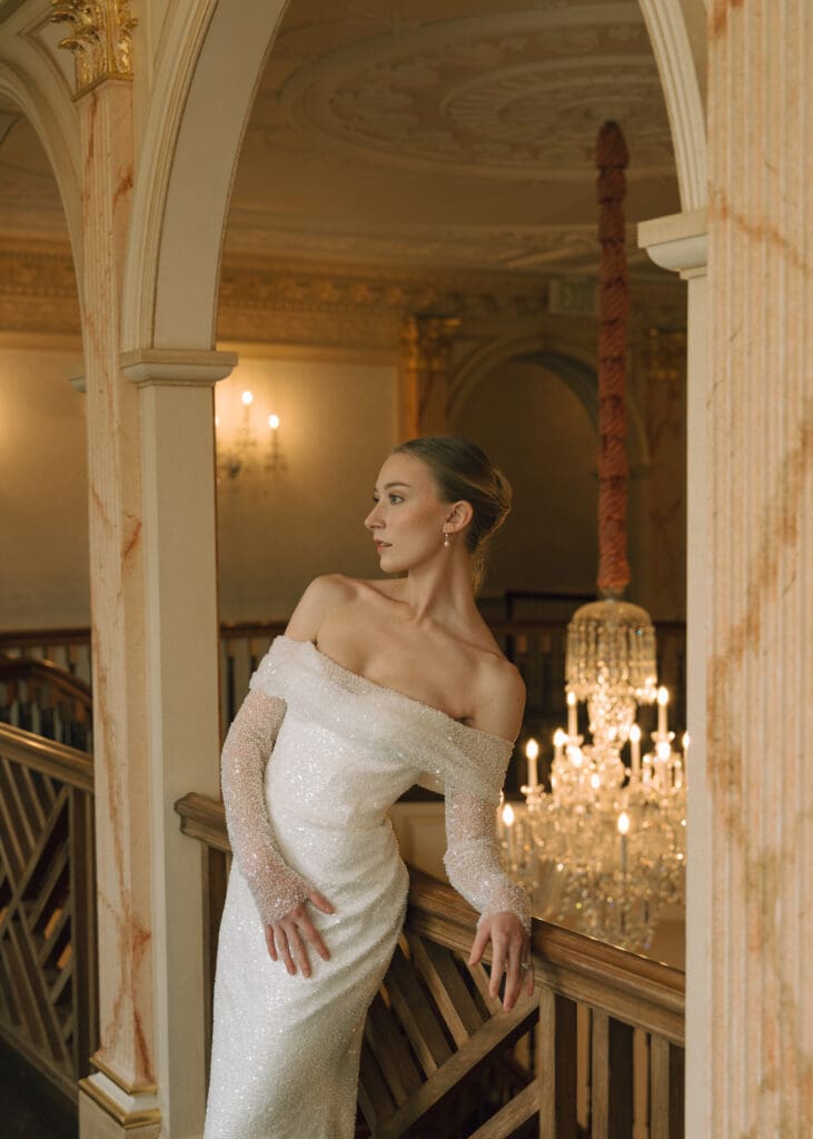 bride leaning against the railing in sparkly dress 