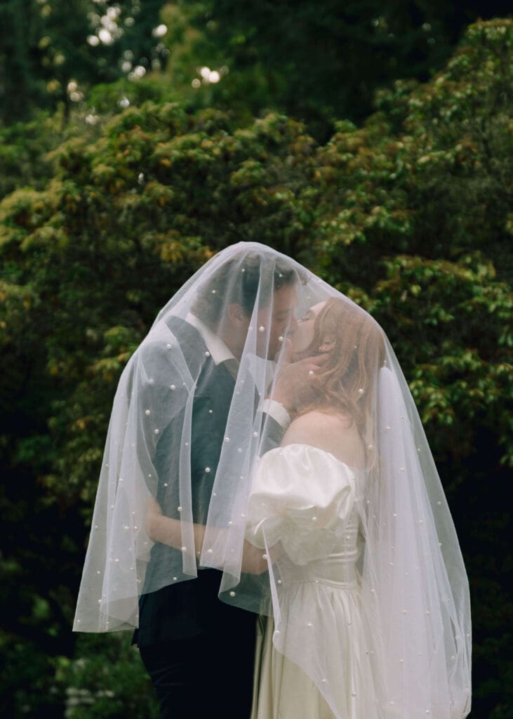 bride and groom kissing under a veil 