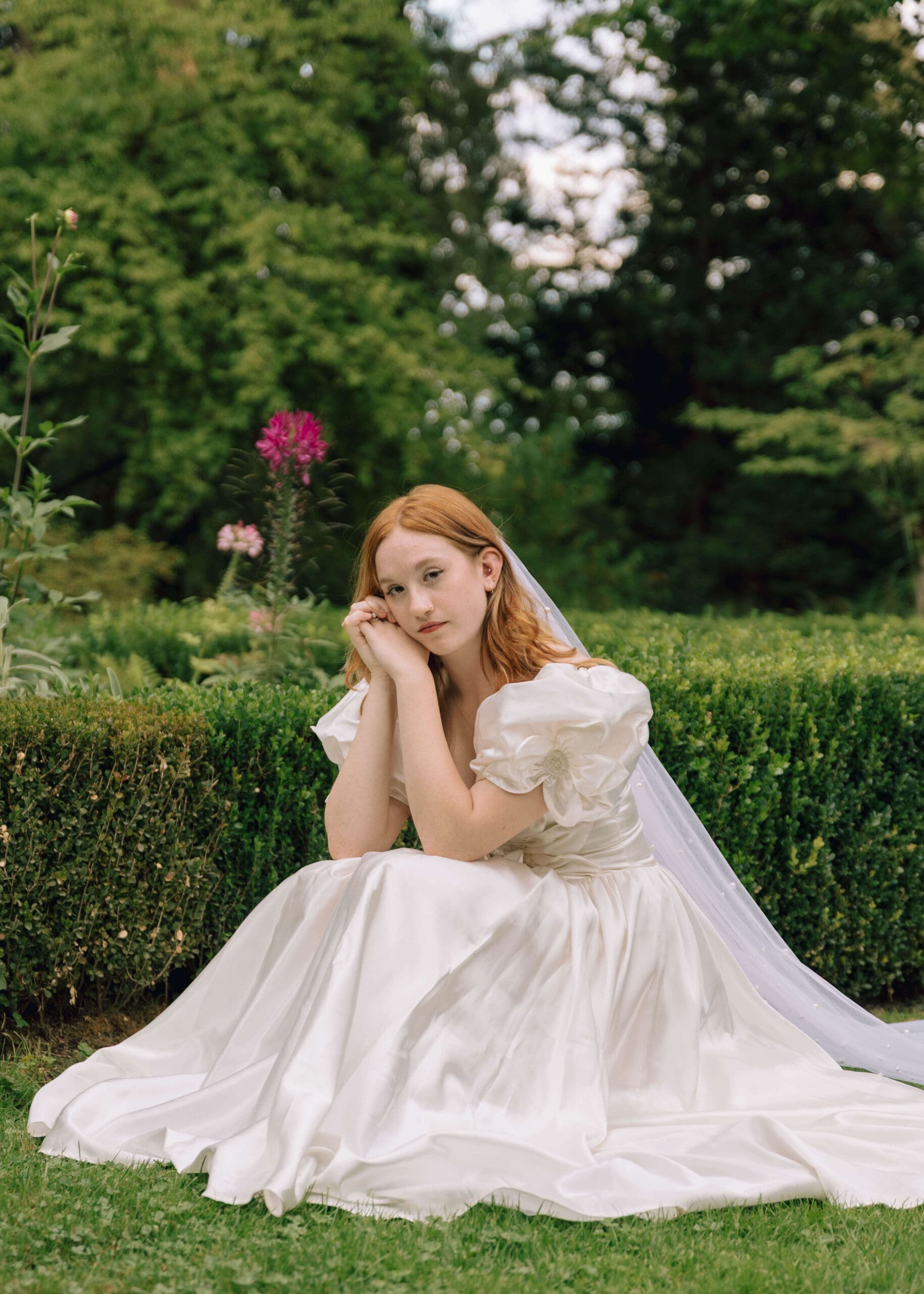 bride crouching in the garden with her hands touching her face at Thornewood Castle wedding