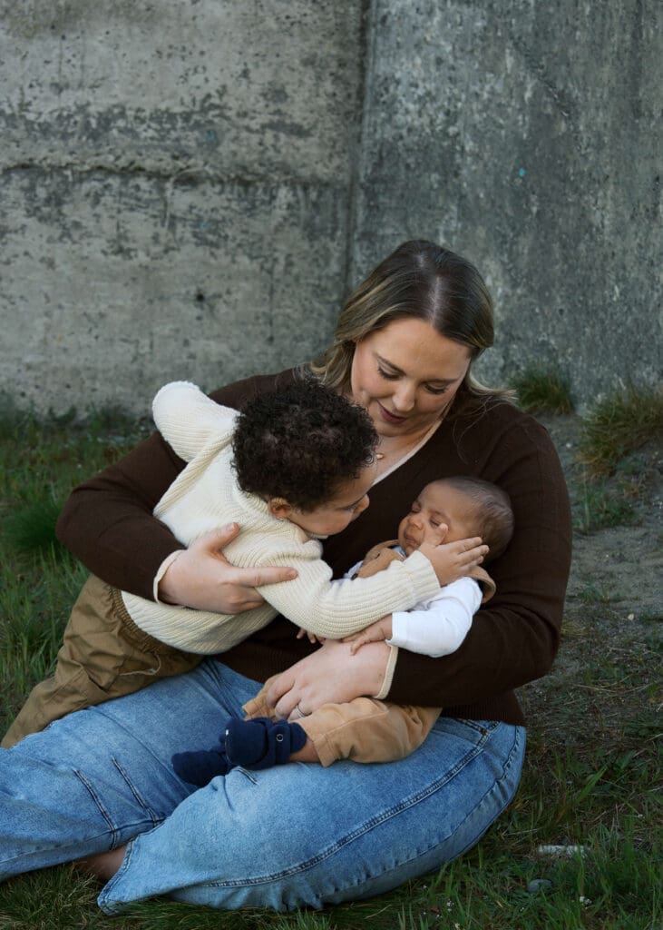 mother holding sons for Chambers Bay family photos while toddler cups baby's face