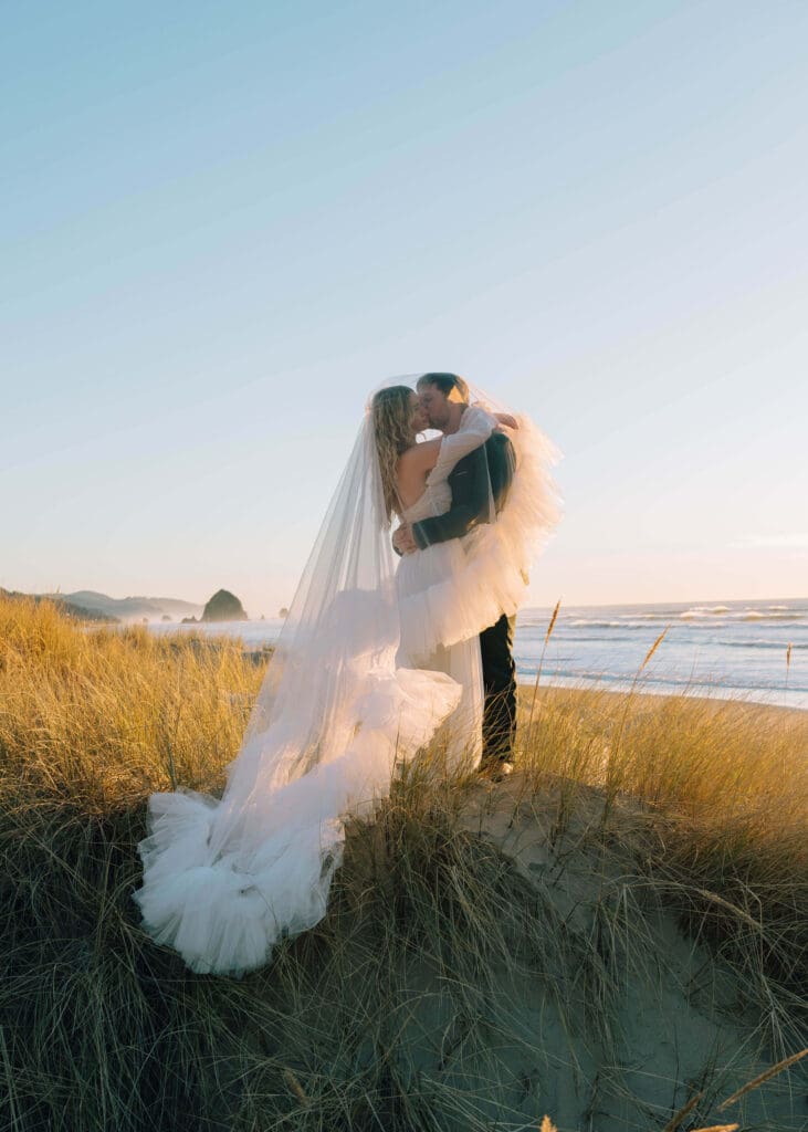 groom kissing his bride on the cheek by Ecola state park elopement photographer