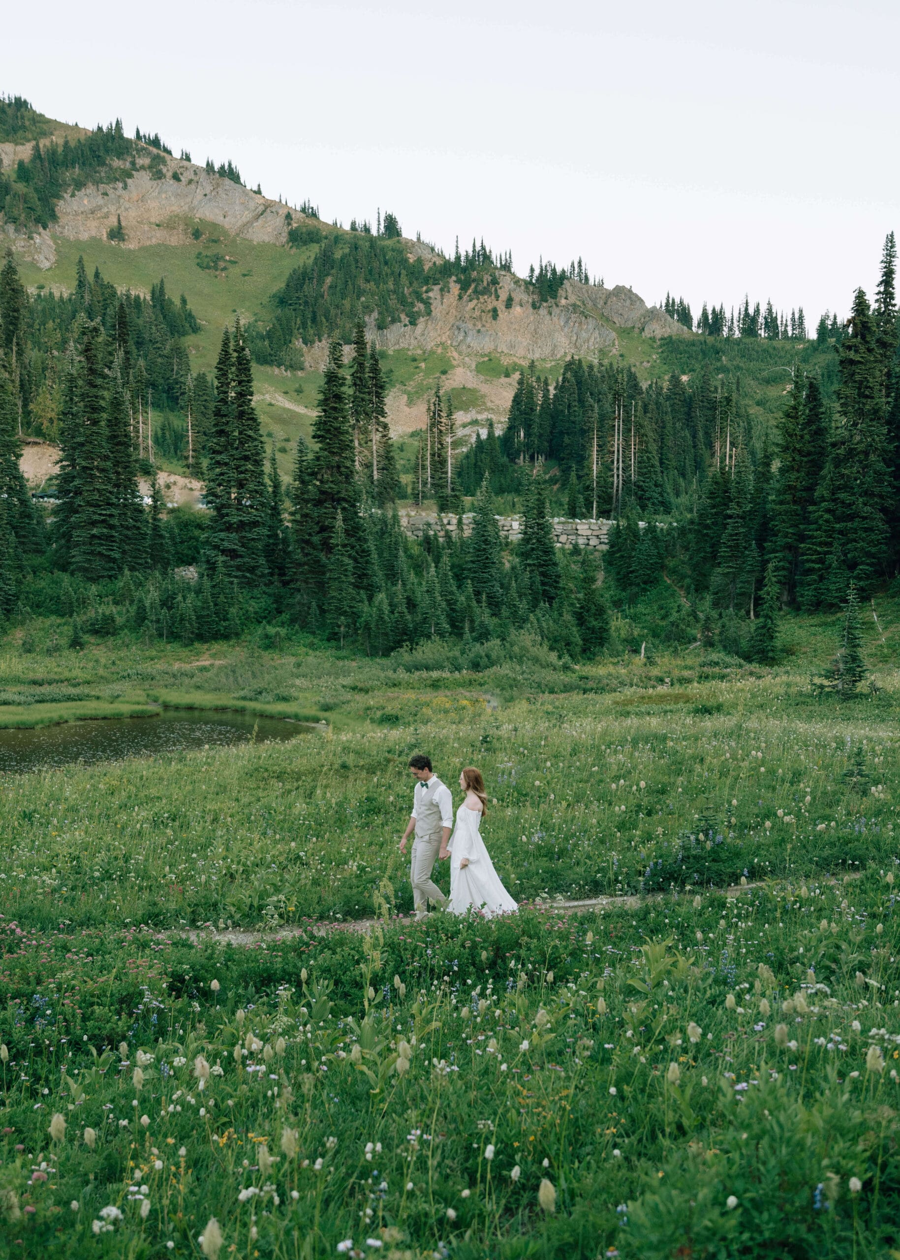 couple holding hands and walking among the wildflowers at Mt Rainier engagement photos