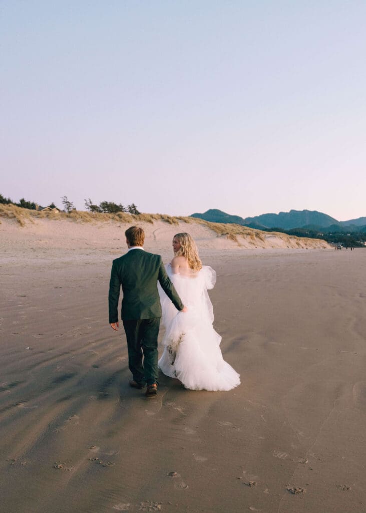 couple walking on the beach at blue hour after oregon coast elopement 