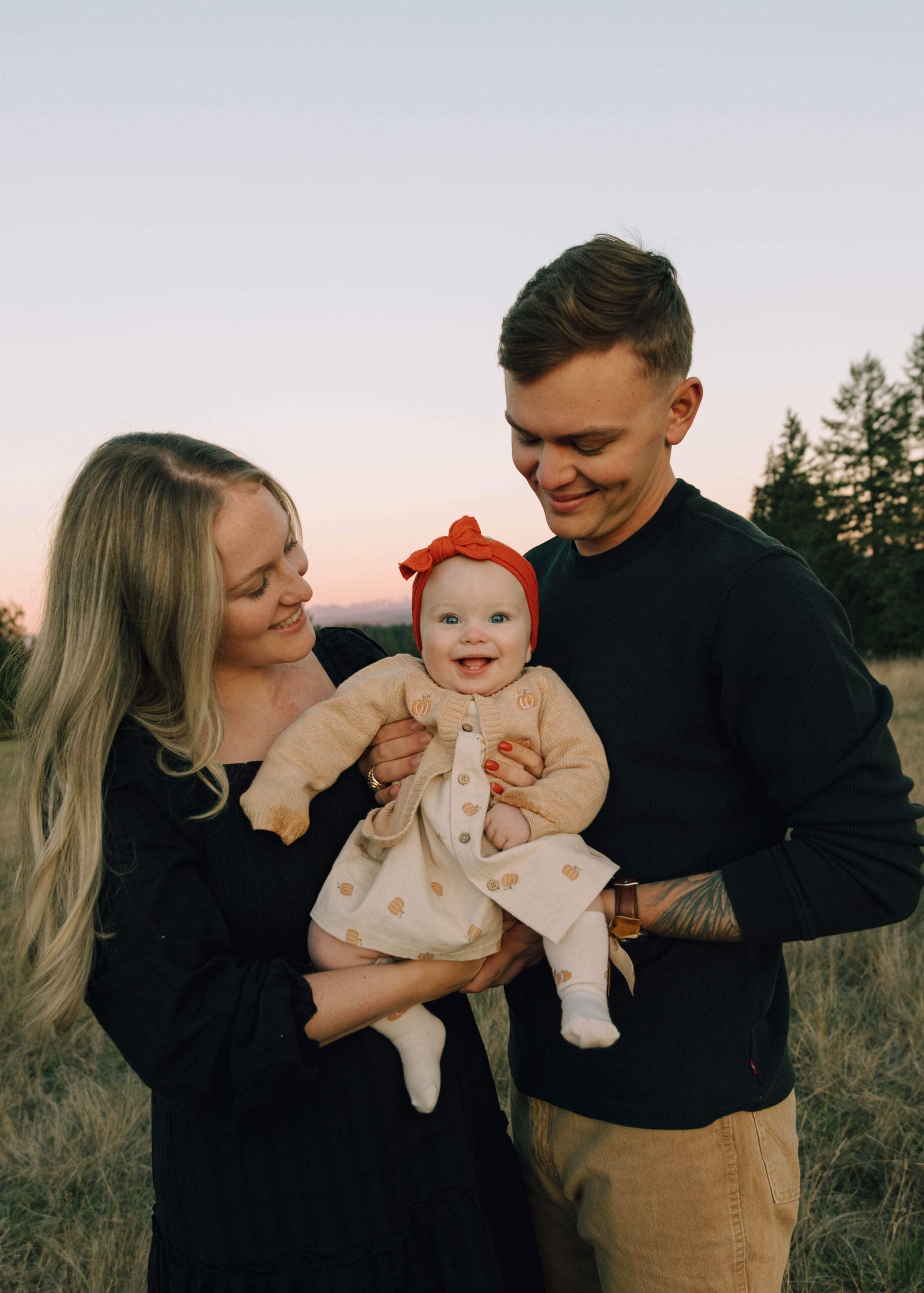 parents holding smiling baby in the fall for family photos