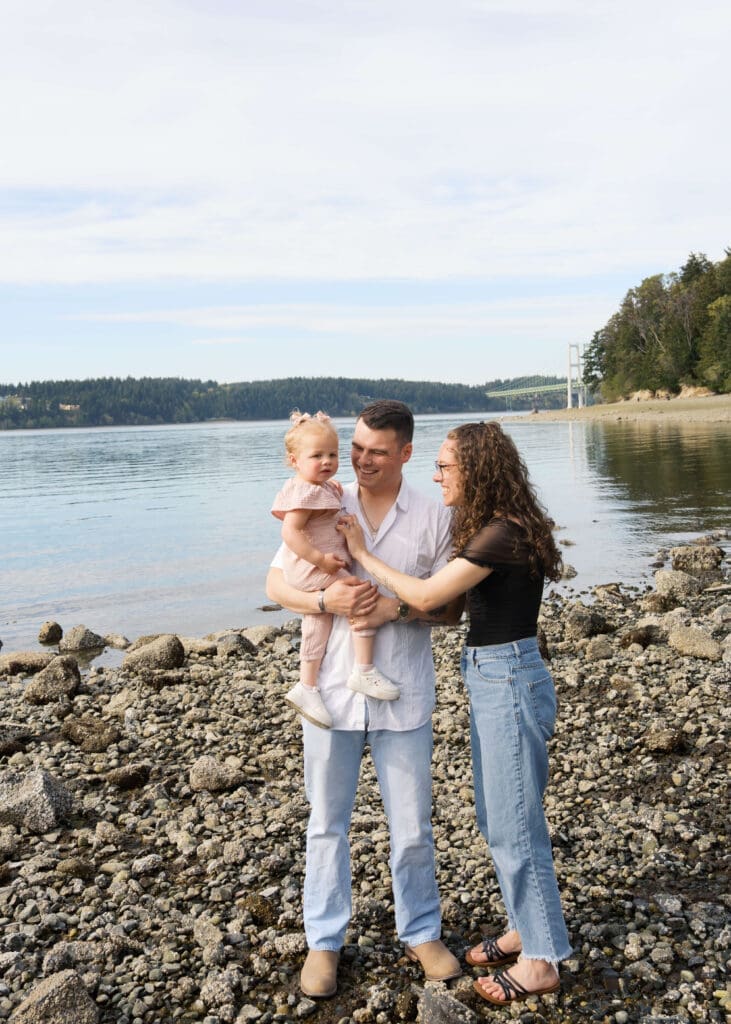 mom and dad holding toddler girl and tickling her for Titlow beach family photos