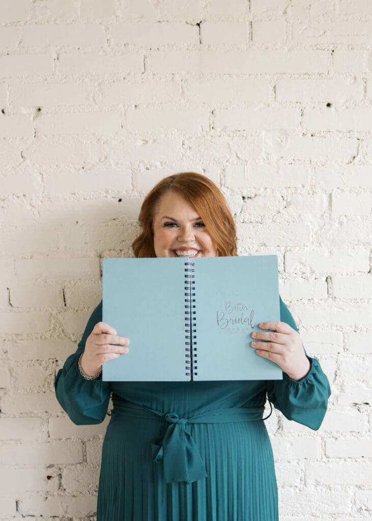 wedding planner peeking over blue book and smiling 