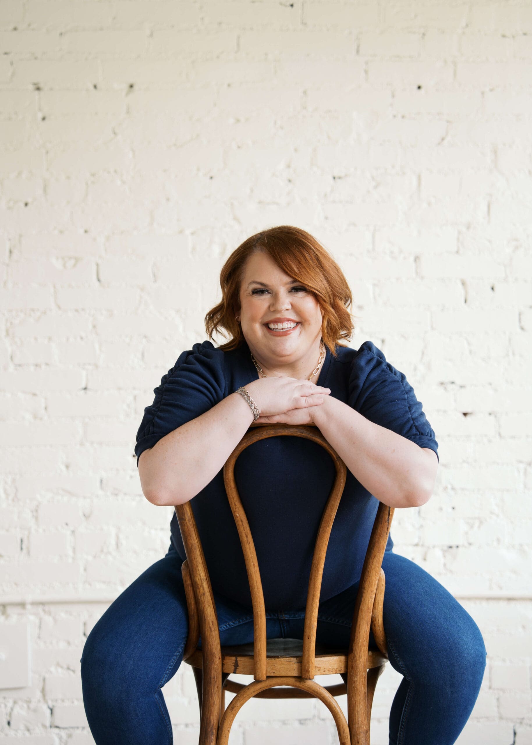 redhead wedding planner sitting on a chair backwards