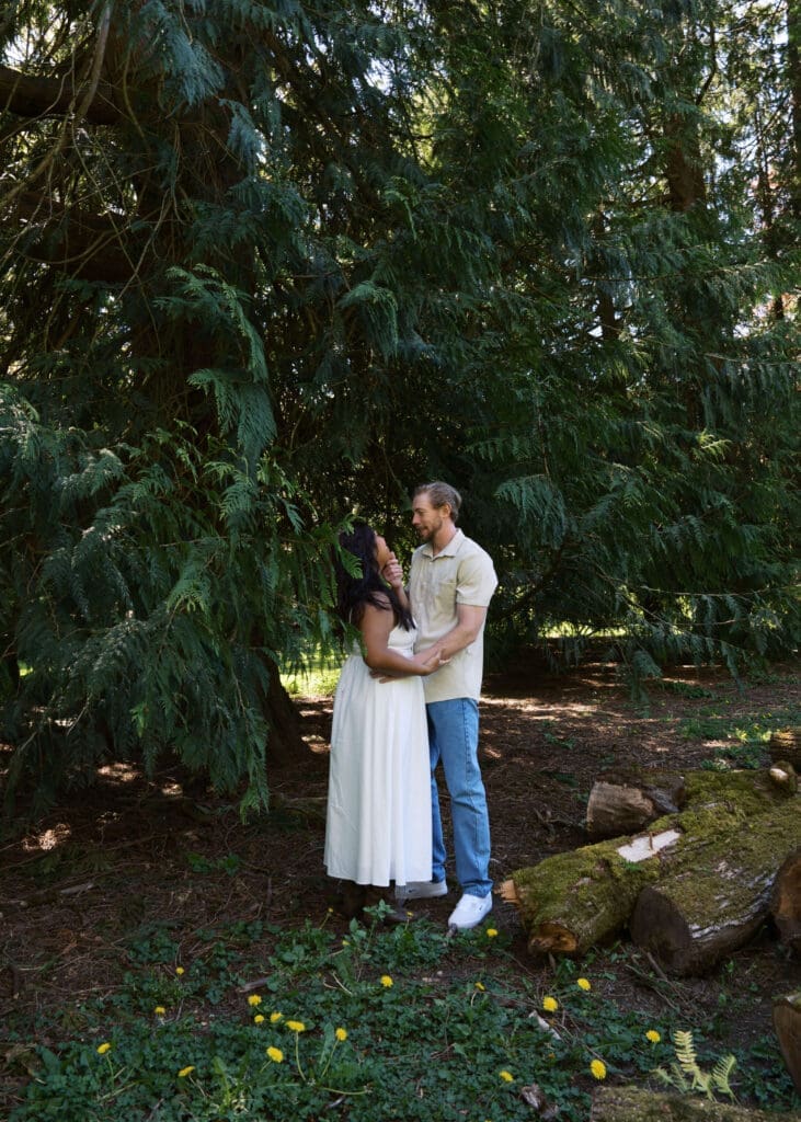 man cupping his partner's face in the trees in Spring for Seattle engagement photos