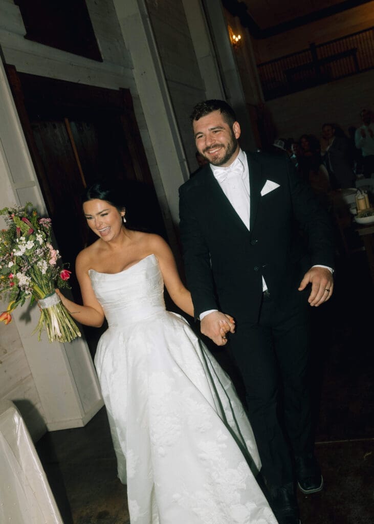 smiling bride and groom making a grand entrance to wedding reception