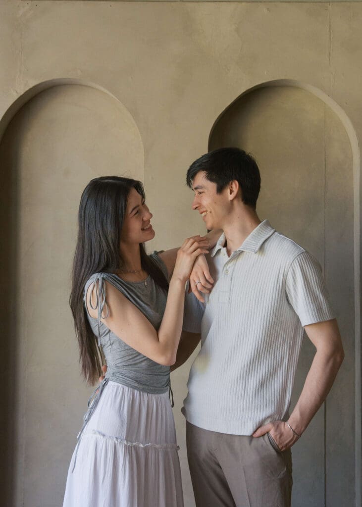 woman leaning on partner's shoulder and looking at him at Seattle photo studio wearing white and grey 