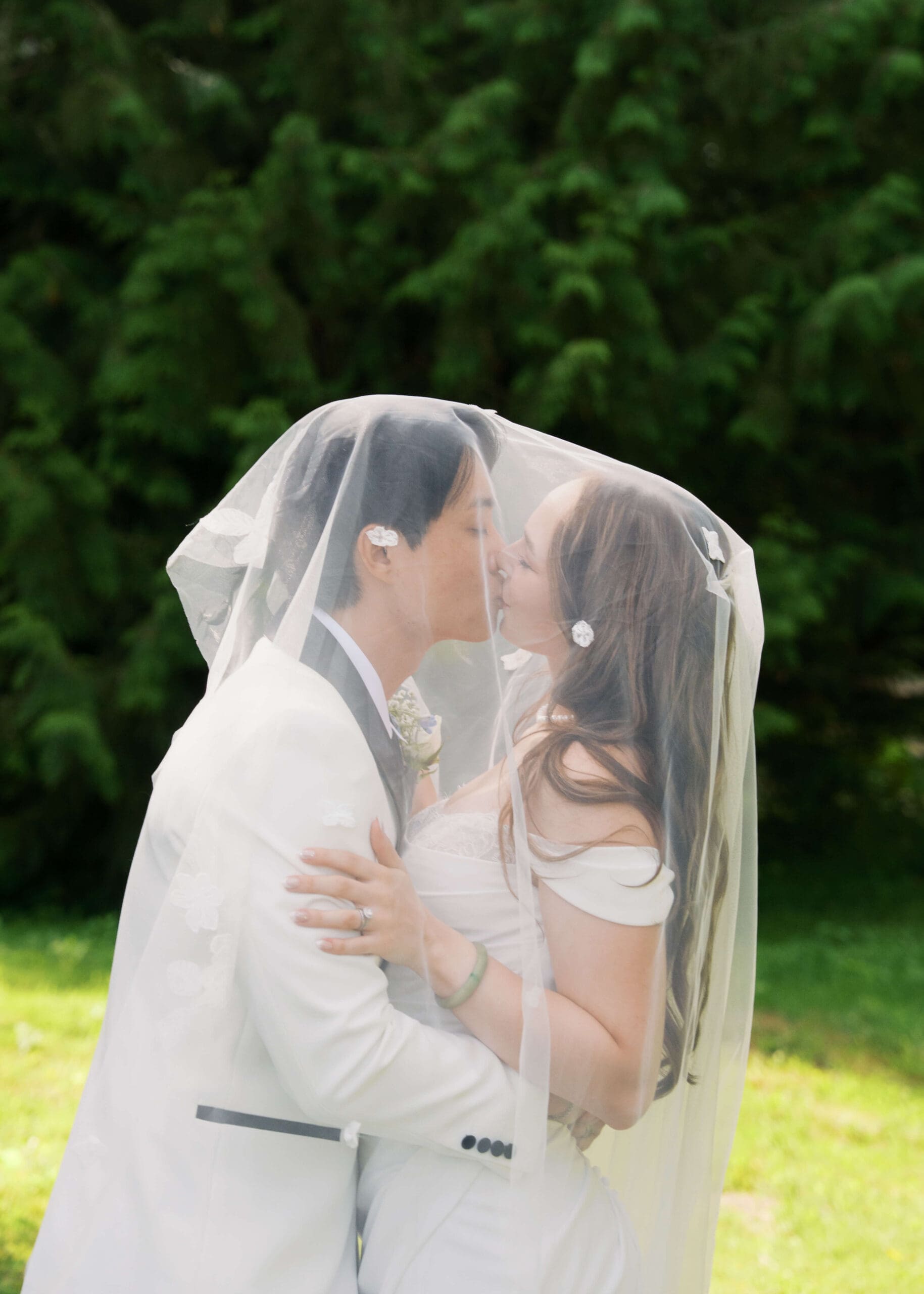 bride and groom kissing under a veil at outdoor wedding in Georgia