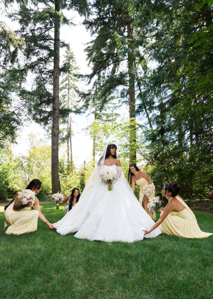 bridesmaids in yellow dresses fix the bride's dress for photos outside at Hidden Stone Palace