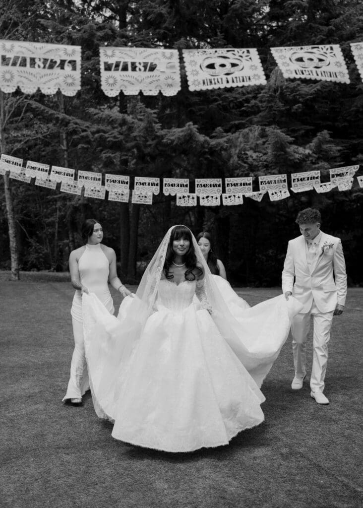 bride walking while her husband and bridesmaids hold her dress at Hidden Stone Palace