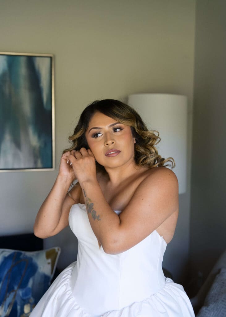 bride putting in her earrings the morning of her wedding