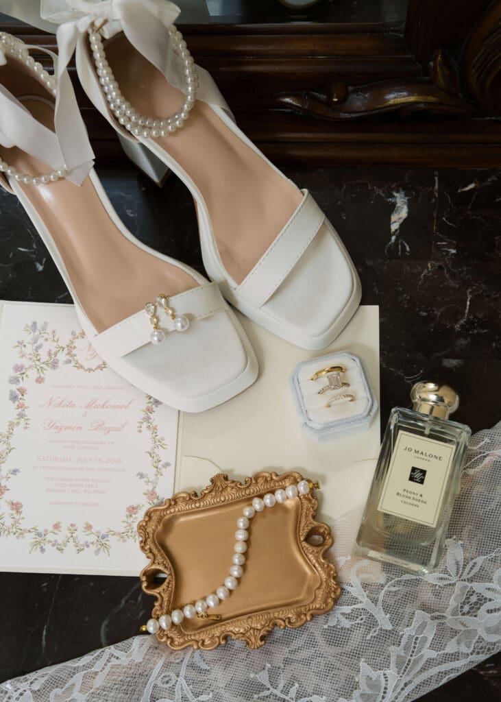 flat lay photo with shoes, earrings, rings, invitation, pearls, perfume and gloves