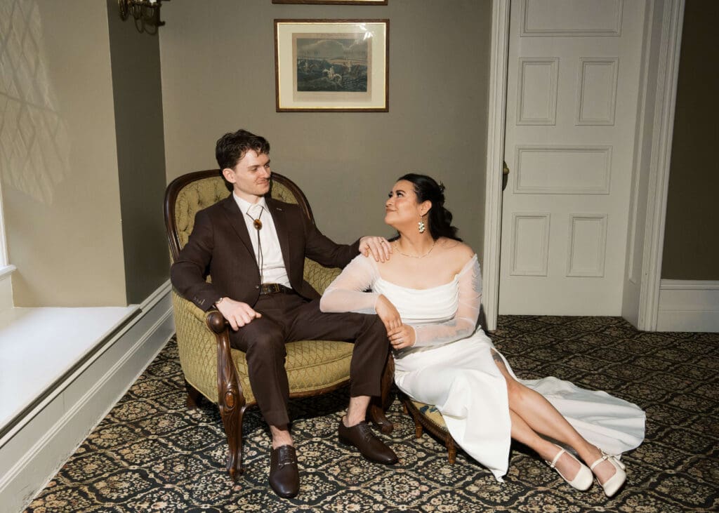 bride sitting on the floor and leaning on her groom's leg while he sits in a chair at Stimson-Green Mansion