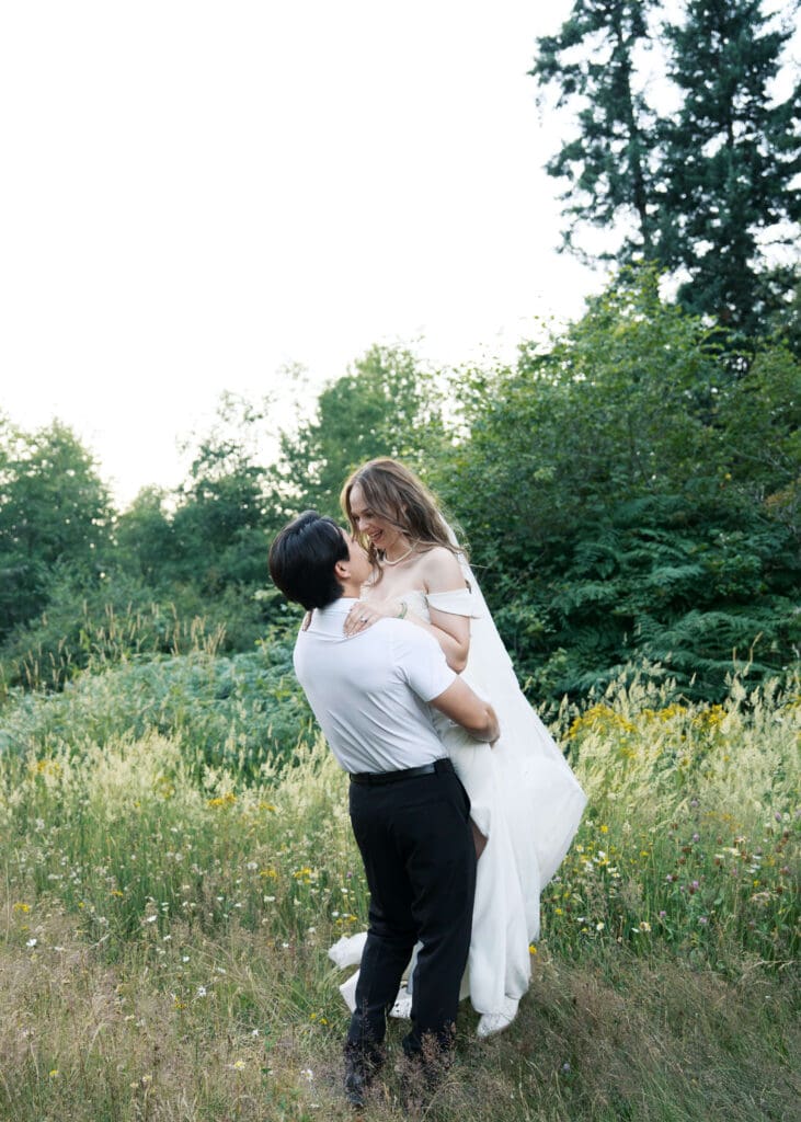 groom lifting his bride up at sunset at the lodge at trinity tree farm