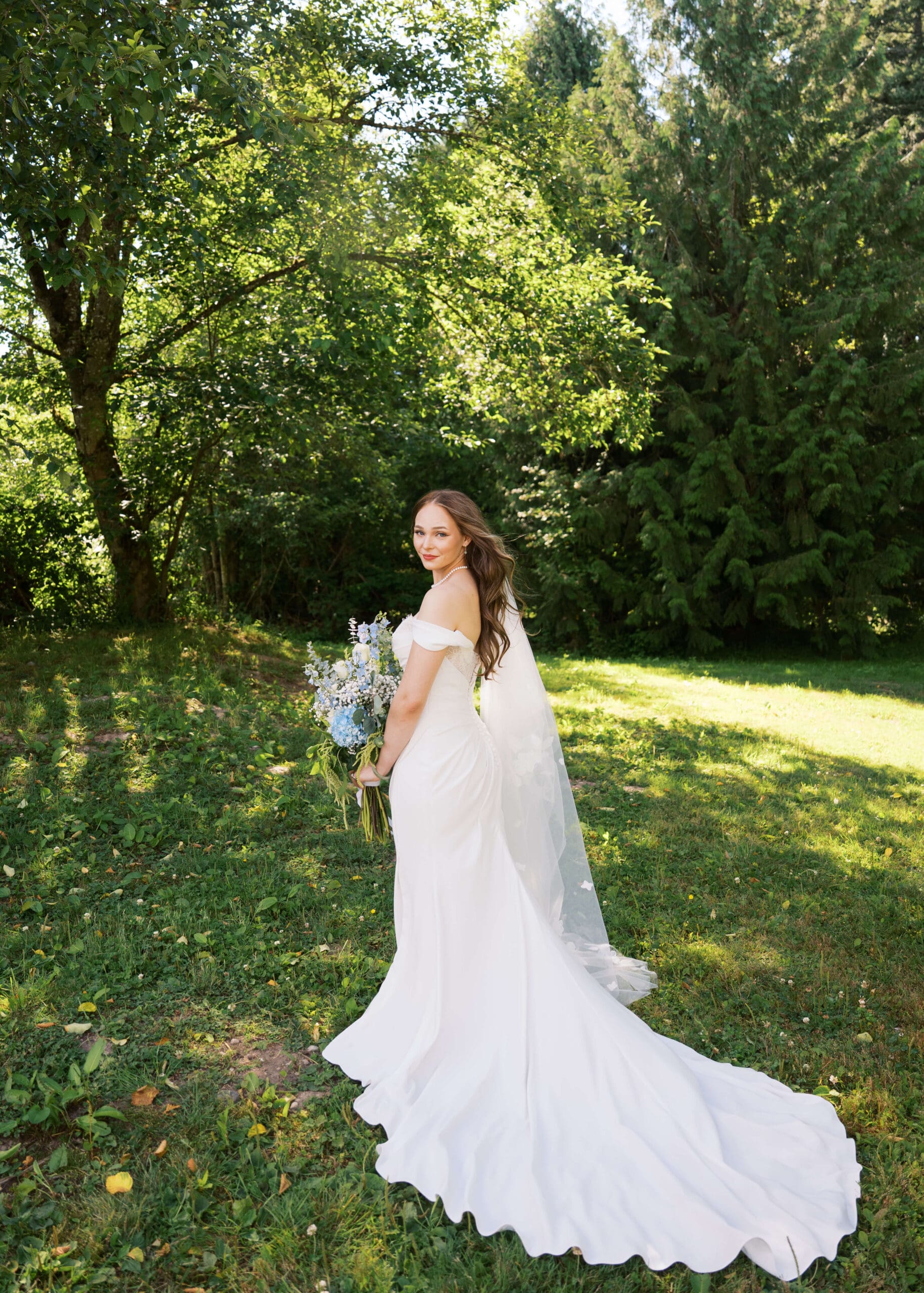 bride outside in the PNW looking over her shoulder holding her bouquet