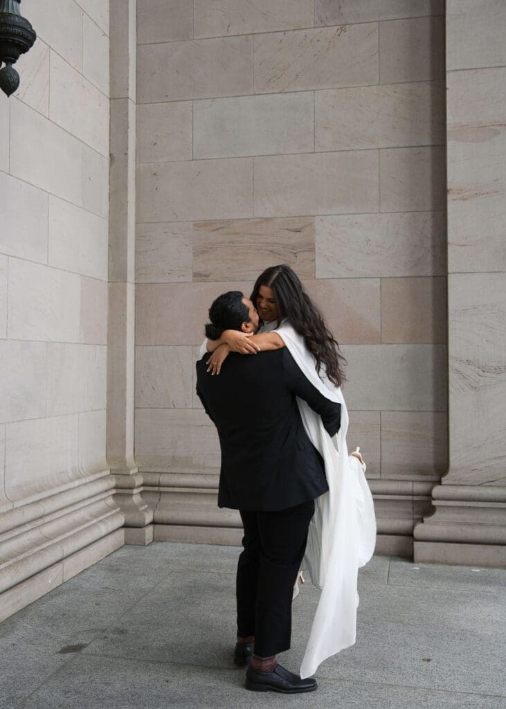 groom picking up his bride and spinning her around at the Washington state capitol building in Olympia 